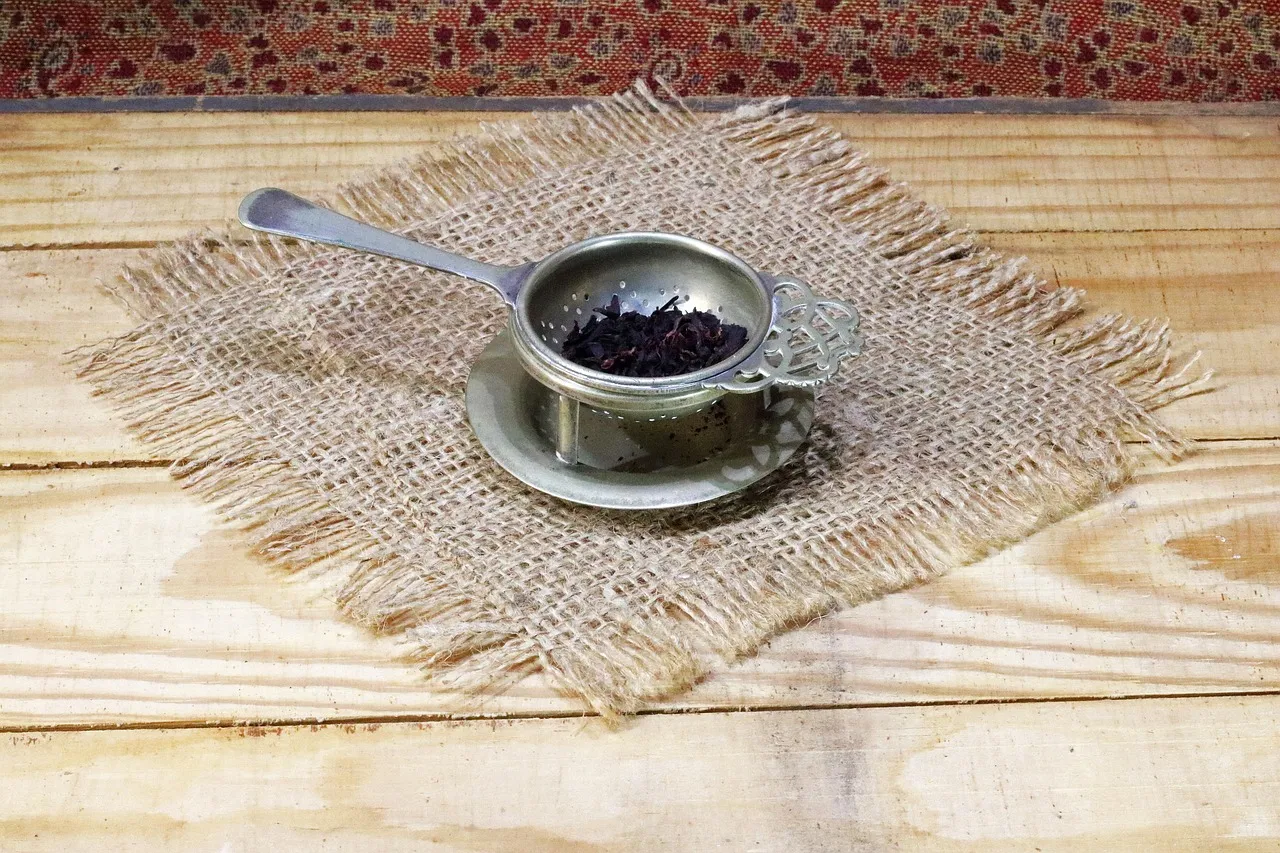 Une passoire à thé en laiton sur une soucoupe, sur une table en bois