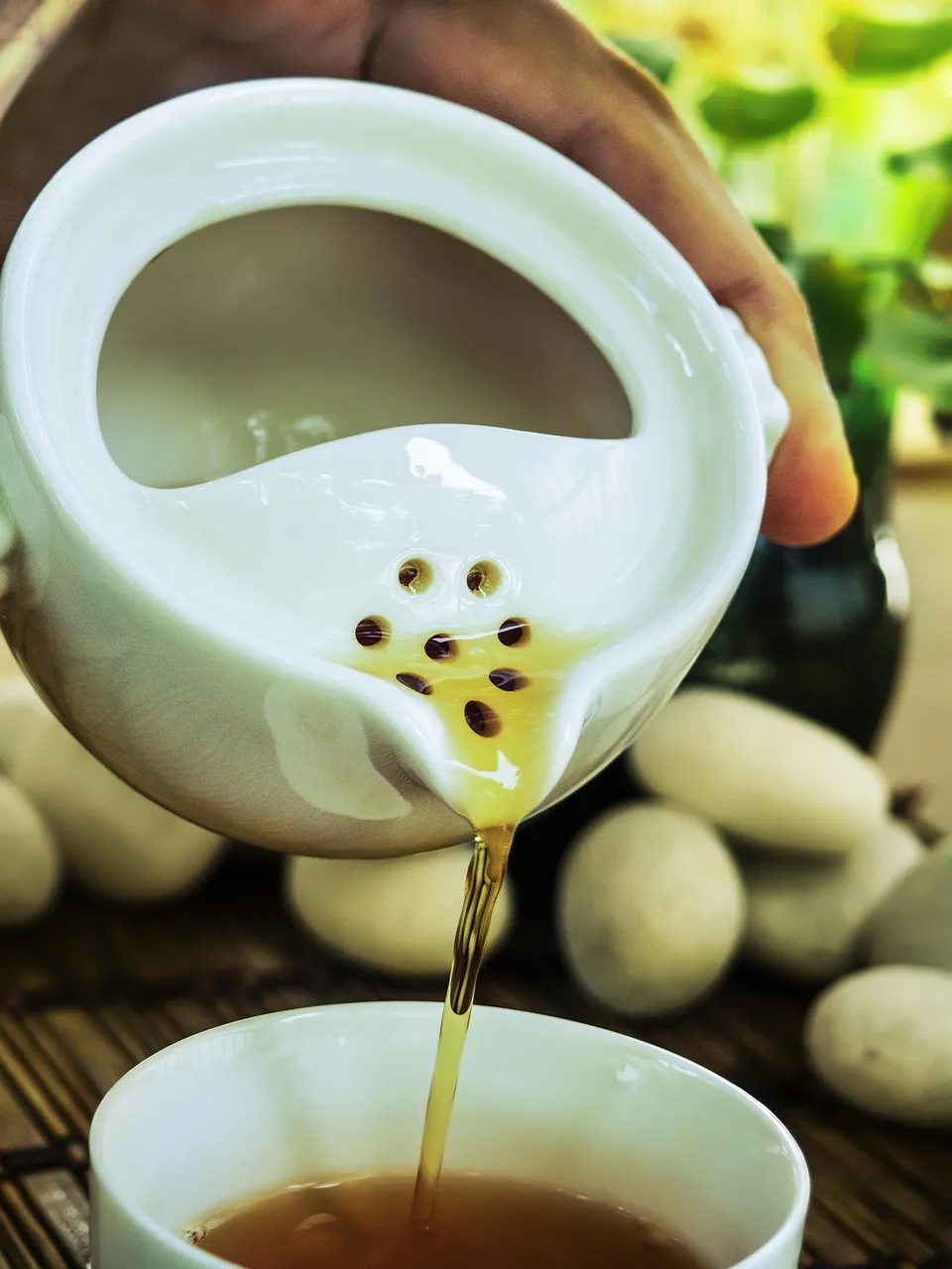 Un thé pâle versé à travers une passoire en porcelaine blanche