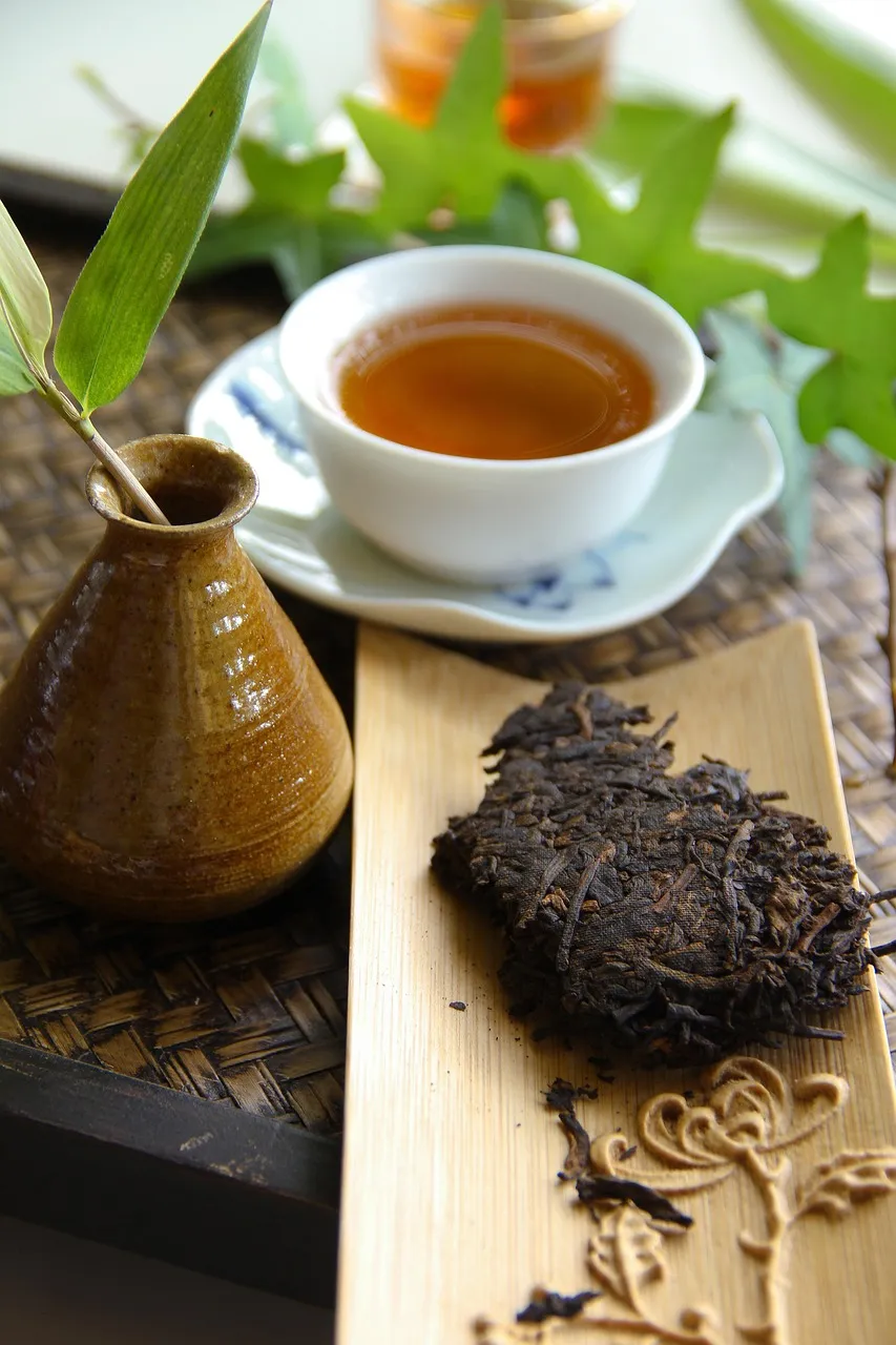Un morceau de galette de pu-erh compressé à côté d’une tasse de thé sombre